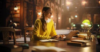 Klasik Kütüphanede Çalışmak İçin Dizüstü bilgisayar kullanan çok ırklı Asya Koleji Öğrencisi. Güzel Genç Kadın İnternette Öğreniyor, Hazırlanıyor