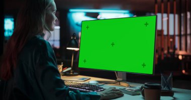 Omzunun Üzerinde: Yaratıcı Ajans 'ta Chroma Key Ekranı ile bilgisayar üzerinde çalışan beyaz kadın uzman. Masasında oturan genç bir kadın.