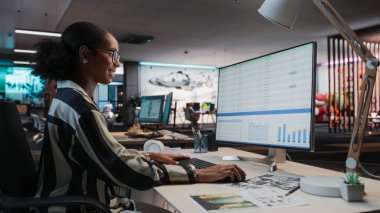 Afrika Kadın Yöneticisi, Analitik Yazılım ve Finans Raporları ile Masaüstü Bilgisayarı kullanıyor. Oyun Geliştirme Şirketi Çeşitli Ofislerinde Çalışan Kadın