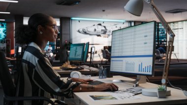 Afrika Kadın Yöneticisi, Analitik Yazılım ve Finans Raporları ile Masaüstü Bilgisayarı kullanıyor. Oyun Geliştirme Şirketi Çeşitli Ofislerinde Çalışan Kadın