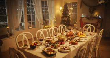 Şükran Günü yemeği ya da Noel Kutlaması Aile Yemeği. Hindi ziyafeti, fırınlanmış patatesle yemek masasının arkasında oturan insanlar.