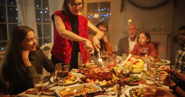 Lezzetli Yemekler ve Festivalsel Dekorasyonlarla Yemek Masasında Oturan Mutlu Misafirler. Genç Dişi, Evdeki Aile Yemeği İçin Bir Hindi oyuyor