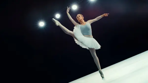 stock image Dedicated Ballet Dancing Ballerina in White Tutu Performs High Grand Jete Under Bright Stage Lights, Her Precision, Grace, and Athleticism in