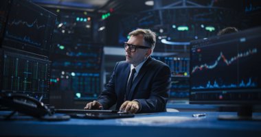 Akıllı ve düşünceli bir borsa simsarının portresi. Gözlüklü Adam Bilgisayar Ekranlarına Bakıyor, Borsa Verilerini Analiz Ediyor