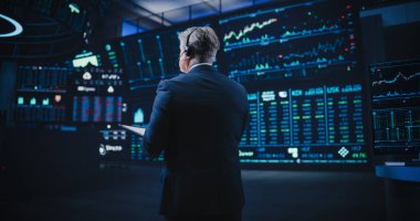 Modern bir borsa şirketinde, yerde çalışan orta yaşlı bir adamın sırtından çekilmiş. Şirketleri, Fonları ve Menkul Kıymetleri İzleme Uzmanı