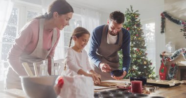 Tatilleri Kutlayan Aile: Ebeveynler ve Çocuk Noel 'de Birlikte Yemek Yapıyor. Tatlı küçük kız ve ailesi zencefilli kurabiye yapıyor. Mutlu