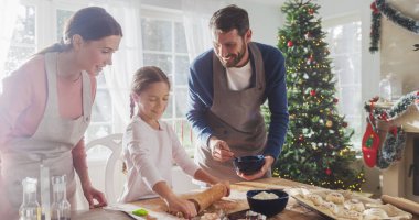 Tatilleri Kutlayan Aile: Ebeveynler ve Çocuk Noel 'de Birlikte Yemek Yapıyor. Tatlı küçük kız ve ailesi zencefilli kurabiye yapıyor. Mutlu