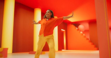 Parlak Kıyafetli Güzel Siyah Kadın Geometrik Soyut Portakal ve Sarı Çevrede Enerjik Dans Ediyor. Modern Dansçı Yaratıcı Genç Kadın