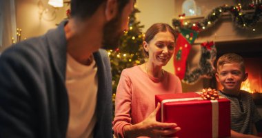 Noel arifesinde Mutlu Aile: İlgili ve düşünceli Koca Tatili Kutlarken Karısına Bir Hediye Veriyor. Paylaşılan Sevgi ve Bakım Anları