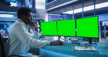 Kanser Araştırma Merkezi Tıbbi Laboratuvarı: Siyah Erkek Nörobilimci Yeşil Ekran Kromakeyli Masaüstü Bilgisayarını Kullanıyor. Uzman