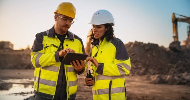 Beyaz erkek inşaat mühendisi İspanyol kadın müfettişle konuşuyor ve yeni bir binanın inşaat alanında tablet bilgisayar kullanıyor. Gayrimenkul
