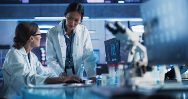 Tıbbi Hastane Araştırma Laboratuvarı: Beyaz ve Asyalı kadın bilim adamları insan beyni tomografisi ile konuşuyor ve bilgisayarlarını kullanıyorlar. Cerrah