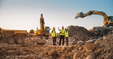 Sunny Day 'de Kazıyıcılarla İnşaat Alanı: Erkek ve Kadın Emlakçılardan oluşan Çeşitli Takımlar Projeyi Tartışıyor. Mühendis, Mimar