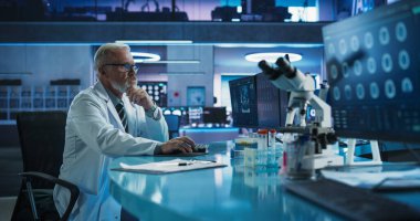 Kıdemli Erkek Nörobilimci, Tıbbi Araştırma Merkezi 'ndeki MRI taramalarını analiz etmek için Masaüstü Bilgisayarını kullanıyor. Kafkas Cerrahı CT çalışıyor.