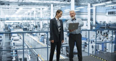 Orta Çağ Mühendisi ve Kadın Bilimadamı Bilgisayarı Kullanıyor ve Modern Üretimle Bir Fabrika Tesisinde Konuşuyor