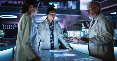 Modern Hastane Tıbbi Araştırma Merkezi: Etkileşimli Dokunmatik Ekran Masası etrafında toplanmış çeşitli meslektaşlar tomografisi çekilmiş beyin taramaları. Doktorlar.