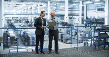 Orta Çağ Mühendisi ve Genç Kadın Teknisyen Konuşuyor ve Dizüstü Bilgisayar Kullanıyor. Sistem Raporları İzleme ve Analiz Uzmanları