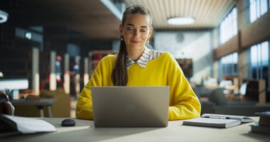Bir Kütüphane Okuma Salonunda Sınıfa Hazırlık Yapan Genç Öğretmen. Bir Üniversite Araştırma Projesinde Çalışmak için Dizüstü bilgisayar kullanan Başarılı Kadın