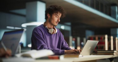 Defterde Yazan Kişi. Kütüphanede çalışmak için dizüstü bilgisayar kullanan düşünceli bir kolej öğrencisine odaklan. Yakışıklı Adam Öğreniyor
