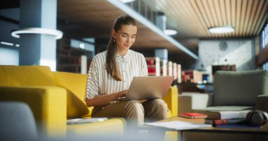 Uluslararası Girişim Ofisinde Dinlenme Alanında Çalışan Genç Kadın Uzman. Yönetici dizüstü bilgisayarını kucağında tutuyor, interneti tarıyor