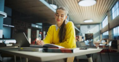 Bir Kütüphane Okuma Salonunda Sınıfa Hazırlık Yapan Genç Öğretmen. Bir Üniversite Araştırma Projesinde Çalışmak için Dizüstü bilgisayar kullanan Başarılı Kadın