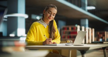 Avrupa Koleji öğrencisinin bir halk kütüphanesinde çalışmak için dizüstü bilgisayar kullanması. Güzel Genç Kadın İnternette Öğreniyor, Sınavlara Hazırlanıyor