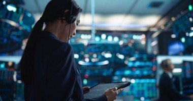 Borsa katında Tablet Bilgisayar 'da çalışan genç Asyalı Kadın Simsar. Gerçek zamanlı hisse senedi, emtia ve borsayı izleyen tüccarlar