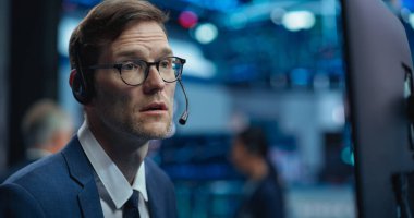 Akıllı ve düşünceli bir borsa simsarının yakın portresi. Gözlüklü Yetişkin Adam Bilgisayar ekranına bakıyor, Bir istemciyle iletişim kuruyor