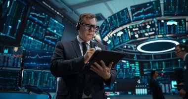 Stresli Koşullar Altında Profesyonel Borsa İşlemcisi. Borsa komisyoncusu telefonda müşterilerle konuşuyor, Tablet üzerinde çalışıyor.