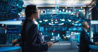 Borsa katında Tablet Bilgisayar 'da çalışan genç Asyalı Kadın Simsar. Gerçek zamanlı hisse senedi, emtia ve borsayı izleyen tüccarlar