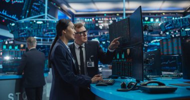 Asya Kadın ve Erkek Menkul Kıymetler Borsası Ajanları Masaüstü Bilgisayarını Kullanıyor, Uluslararası Bir İşadamı için Yatırım Stratejisini Tartışıyor,