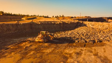 Güneşli bir günde inşaat alanının hava aracı görüntüsü endüstriyel yükleyicinin bir binanın temelini atmak için kayalardan bir alanı temizlemesi. Kişi Kullanımı