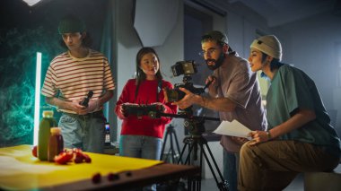 Çeşitli genç film ekibi, modern ekipman ve renkli aksesuarlarla çevrili canlı bir sette yaratıcı bir video prodüksiyon seansına katıldı.