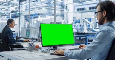 Bir Fabrika Ofisinde Yeşil Ekran Kromakey Mock Up ile bir Masaüstü Bilgisayarı üzerinde çalışan Robot Mühendisi. Teknolojik Araştırma ve
