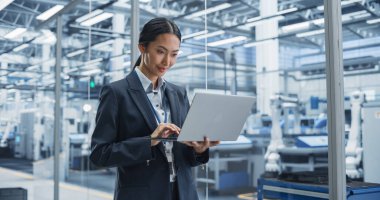 Asya Fabrikası Yöneticisi, özerk Robotik Kurulum Hattı ile birlikte Fütüristik Endüstriyel Üretim 'de Laptop üzerinde çalışıyor. Uzman İzleme Üretimi