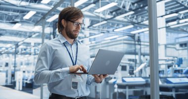 Gözlüklü Yakışıklı Bir Mühendisin Portresi Laptop Bilgisayar Kullanıyor ve Modern Elektronik Üretimle Bir Fabrika Tesisine Bakıyor