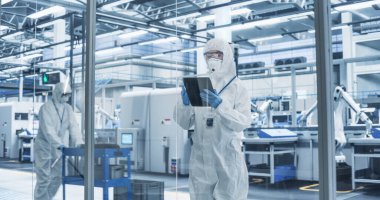 Biyoteknoloji Üretim Tesisinde tüm vücudunu koruyan koruyucu kaplama, maske ve gözlük takan bir kadın işçinin portresi. Genç Uzman Kullanıyor