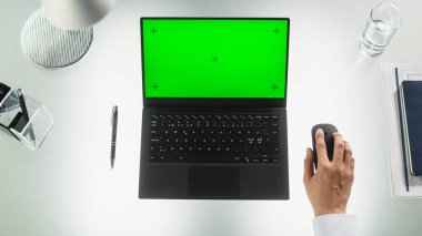 Anonim Şirket Çalışanı Laptop Bilgisayarını kullanarak Yer Tutucularla Yeşil Ekran Kromakey Gösterimi yapıyor. Masanın Arkasında Oturan Adam, Bakınıyor