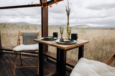 Kahvaltı, öğle yemeği ya da akşam yemeği için masa hazır. Doğanın ortasında panoramik pencereli iki kişilik masa. Yemek, kafe, restoran.