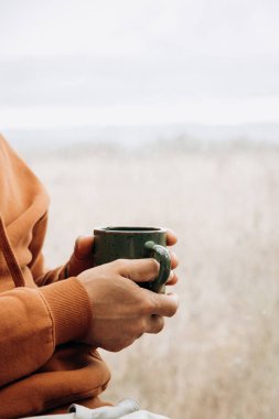 Bir adam kahvaltı masasında yüzü olmayan bir fincan kahve ya da başka bir içecek alır.