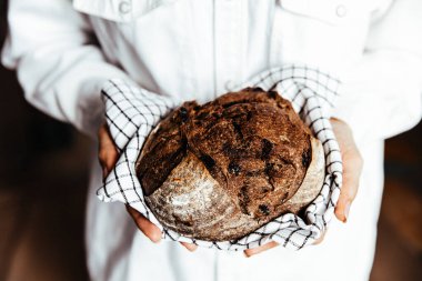 Fırıncının elindeki sepette taze pişmiş ekmek. Pişirme, tam tahıl malzemeleri, besinler, sağlık hizmetleri.