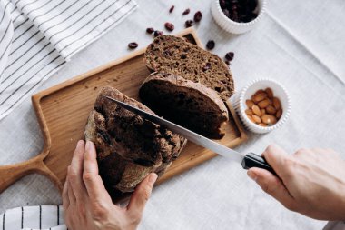 Kadın eli bıçakla kesme tahtasında çavdar ekmeği kesiyor..