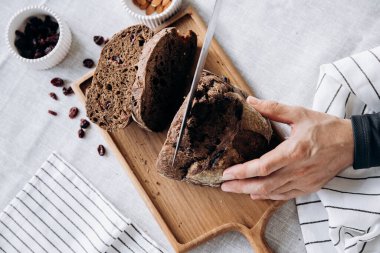 Kadın eli bıçakla kesme tahtasında çavdar ekmeği kesiyor..