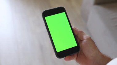 Bir adam elinde yeşil ekranlı bir telefon tutuyor. Telefon ekranınızda kromakey kullanıyorsunuz. Mesaj için yer, resimler. İş, finans, eğitim.