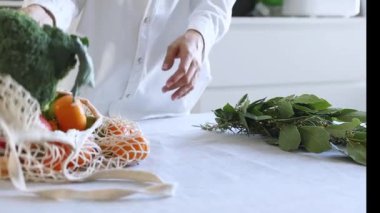 Bir kadın alışveriş yaptıktan sonra alışveriş çantasından taze meyve ve sebze alır. Sağlıklı beslenme ve yaşam tarzı, çevrimiçi ve çevrimdışı alım