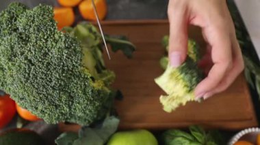 Brokoliyi daha fazla işlem ve pişirme için çiçeklere ayıran bir kadının ellerine yakın çekim. Sağlıklı beslenme ve pişirme konsepti