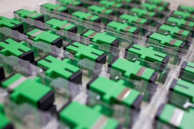 Optical adapters with different connectors in plastic blisters on the table, a batch of goods clipart