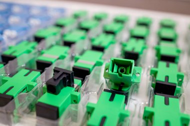 Optical adapters with different connectors in plastic blisters on the table, a batch of goods clipart