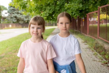 İki mutlu okul çağında kız, sokakta gülümseyen çocuklar, şehir, şehir, açık hava portresi, fotokopi alanı, bulanık arka plan. Yakın arkadaşlar, kız kardeşler, kardeşler birlikte, gerçek insanlar yaşam tarzı.
