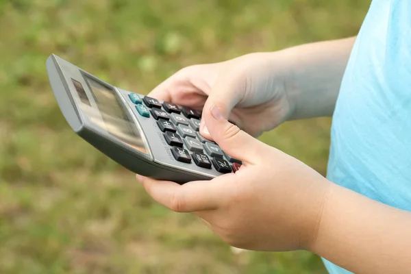 Anonymous elementary school age girl, child using a calculator holding it in hands, object closeup, one person. STEM, math, mathematics learning, education, educational subject, smart kids, science